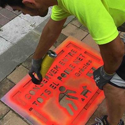 Un membre de la brigada municipal pinta un dels cartells al terra de l'avinguda Lluís Companys.